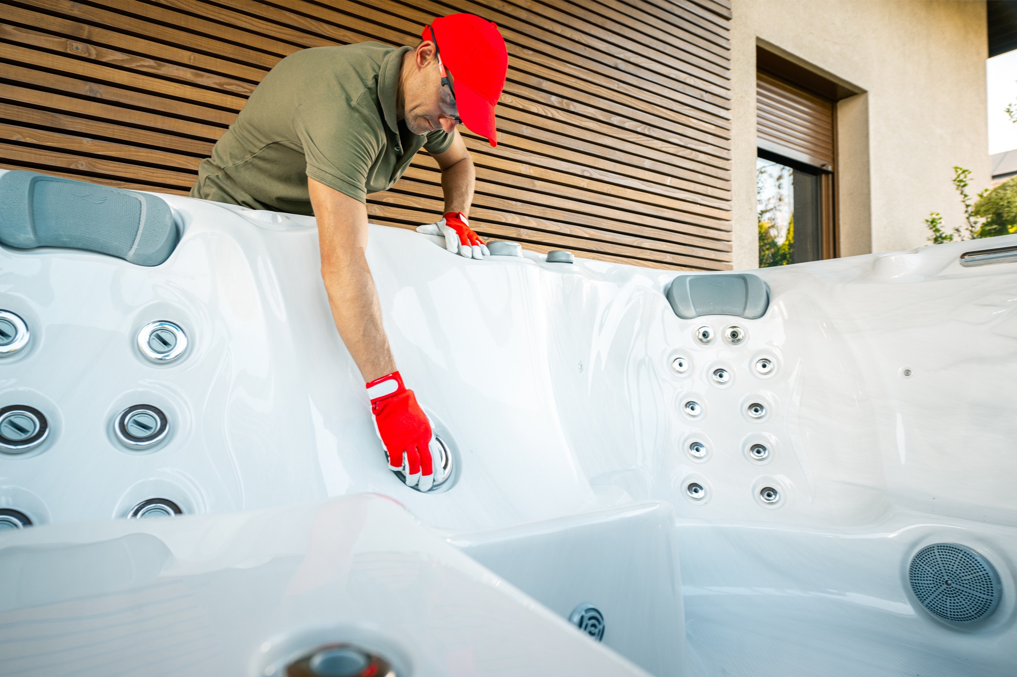 Technician Performing Maintenance on a Hot Tub in a Modern Outdoor Patio Setting at Midday